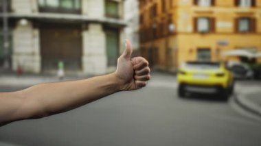 Canlı şehir caddesinde otostop çeken bir adam, şehir mimarisi, binalar ve sarı arabalarla çevrili kollarını kaldırarak seyahat iyimserliğini vurguluyor..