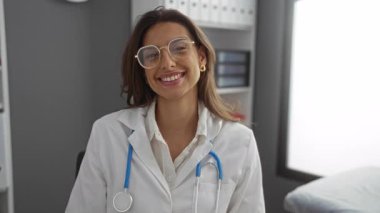 Steteskoplu kadın doktor modern kliniğin iç kısımlarında güvenle gülümsüyor profesyonel sağlık hizmetleri sunuyor..