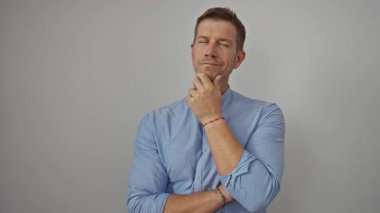 Kollarını kavuşturmuş yakışıklı genç bir adam beyaz bir arka plana karşı bir fikre sahip olma, yaratıcılık ve tefekküre sahip olma jesti..