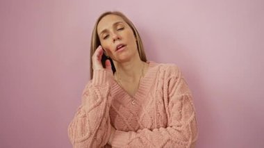 Pembe arka planda baş aşağı dinlenen kadın örgü kazak giyerek yorgun görünüyor. Basit bir portrede yorgunluk yayıyor. Duygularını etkili bir şekilde aktarıyor..