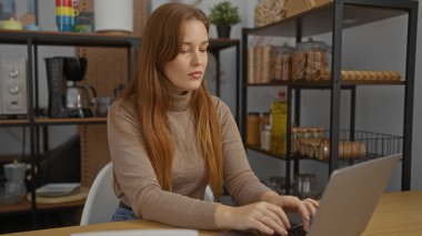 Modern ofis ortamında dizüstü bilgisayarda çalışan bir kadın. Arka planda raflar ve kızıl saçlı, düşünceli bir atmosferi vurgulayan bir kadın..