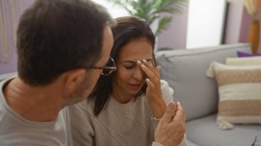 Bir dairede orta yaşlı bir çift duygularını ifade ediyor. Bir erkek, rahat bir oturma odasında kadını rahatlatıyor. Aile ortamında sevgi ve destek tasvir ediyor..