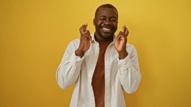 Genç, yakışıklı, afro-amerikalı adam sarı bir arka planda gülümsüyor ve şans diliyor.