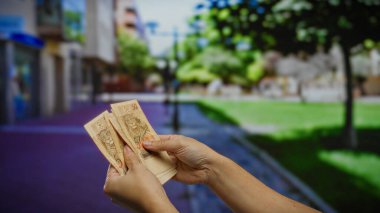 Brezilya Reais 'i elinde tutan adam şehir sokaklarında finans, iş ve döviz kuruna odaklanıyor. Gün ışığında şehir parkında..