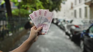 Kalabalık bir şehir caddesinde el ele tutuşan Türk lirası banknotları para ve kültür odaklı finans ve seyahat unsurlarını ön plana çıkaran samimi bir şehir sahnesi çekiyor..