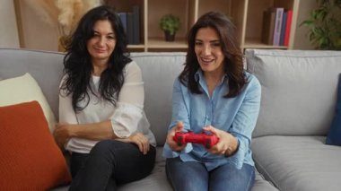 Kanepede oynayan kadınlar, rahat oturma odasında video oyunları oynayanlar, içeride eğlenen orta yaşlı kardeşler..