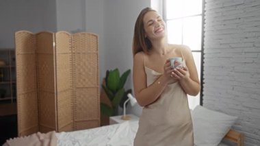 Kadınlar rahat yatak odasında, pencerenin yanındaki yumuşak ışığın altında gündelik giysiler giyerek sabahları kahve içmeyi severler..