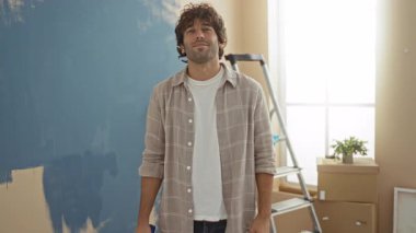 Genç adam oturma odasının duvarını maviye boyarken parlak apartman dekorasyonundan memnun olduğunu gösteriyor..