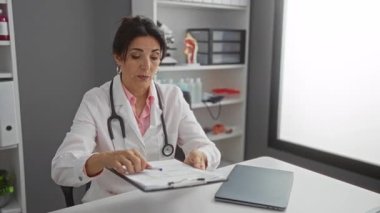 Kadın doktor, bir klinik ofis ortamında, profesyonel sağlık danışmanlığının atmosferini geliştiren tıbbi ekipman ve evrak içeren bir hastayla tartışıyor..