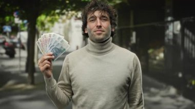 İspanyol bir adam şehrin hareketli bir caddesinde elinde Polonya 'nın zloti banknotları, sıradan bir şehir ortamına güveni yayıyor..