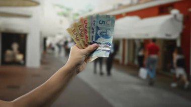 Bir şehir caddesinde Kanada banknotları tutan adam kalabalık bir şehir manzarası yakalıyor..