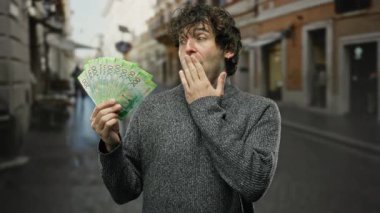 Açık şehir sokak ortamında elinde Rus rublesi tutan adam şaşırmış bir ifadeyle beklenmedik bir servet ya da finansal başarı ima ediyor..