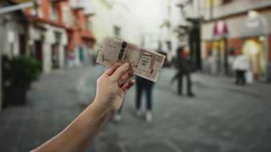 Suudi riyal banknotlarını elinde tutan adam, işlek şehir paralarını ve şehir içi yaşam tarzını gözler önüne seriyor..