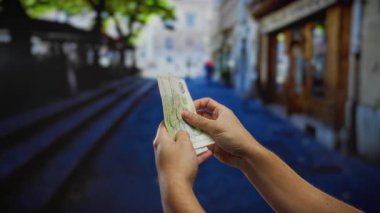 Şehir sokaklarında tek başına dolar sayan bir adam, yoğun bir şehir ortamında yatırım ya da mali işlemlere odaklanıyor..