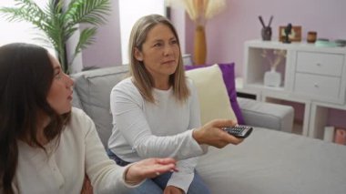 Kadın ve kız rahat bir oturma odasında televizyon seyrediyor. Uzaktan kumandalı rahat bir evde aile sevgisini ve rahatlığını ifade ediyorlar..