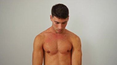 Beyaz arka plan karşısında üstsüz poz veren yakışıklı bir adam. Saf erkeksiliği ve minimalist bir ortamda kendine güveni yakalıyor..