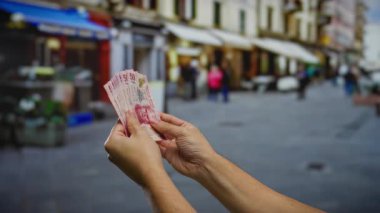 Şehir sokaklarında Meksika pezosu tutan adam canlı bir şehir ortamında iş ve yatırım temaları sergiliyor..