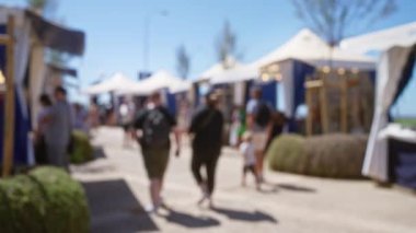 Mallorca 'da açık hava pazarında yürüyen insanları bulanık görmek güneşli mavi gökyüzünün altında yolu beyaz çadırlarla kaplayan.