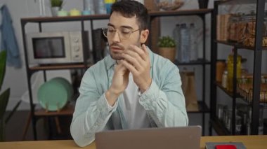 Genç adam, raflar, bitkiler ve dizüstü bilgisayarla çevrili bir ofis ortamında profesyonel ve odaklanmış bir ortam yakalayan ciddi bir ifadeyle bardakları çıkarıyor..