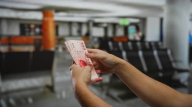Havaalanı terminalinde Tayvan doları sayan bir adam, kapalı alanda seyahat ve mali işlemleri vurguluyor.