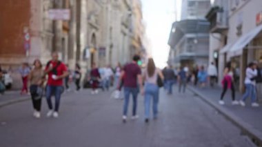 Roma 'da, İtalya' da, aydınlık bir günde güneşli bir günde, bulanık mimari ve canlı şehir yaşamını gözler önüne seren insanlar hareketli bir sokakta yürüyorlar..