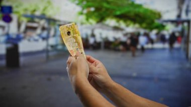 Şehir caddesinde birden fazla Filipinli pezosu tutarken iş ve yatırım temaları bulanık yayalarla dolu kalabalık bir şehir zeminine vurgulanıyor..