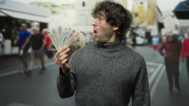 Meşgul bir şehir caddesinde elinde Czech Koruna banknotları tutan adam, dışarıdaki mali durumuyla ilgili şaşkınlığını ve merakını dile getiriyor..