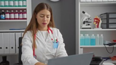 Üniformalı genç bayan doktor, mutlu bir şekilde uzaklara bakıyor, klinikte el ele arıyor, özgüven ve gelecek görüşü gösteriyor.