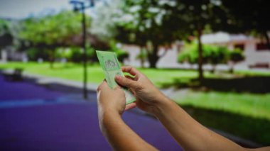 Canlı bir şehir parkı ortamında el ele tutuşan Malezya banknotları, arka planda doğal yeşillik içeren finans temaları tasvir ediliyor.