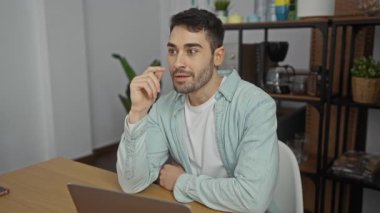 Ofisteki genç bir adam dizüstü bilgisayarla etkileşime geçiyor, dışa dönük ve meşgul bir tavır sergiliyor, iç dekorasyonla çevrili, sıradan bir iş ortamı izlenimi veriyor..