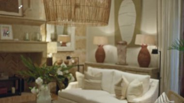 Oturma odası bulanık kanepe, rahat dekor, yumuşak ışıklandırma, hasır abajur, yeşil bitkiler ve nötr tonlarla sıcak, davetkar bir atmosfer yaratıyor..