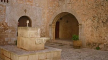 Üniversite kampüsündeki eski bir taş avlunun odaksız görüntüsü sönük ışık altında kavis ve kaldırım taşlarıyla dolu tarihi bir atmosferi ortaya çıkarıyor..