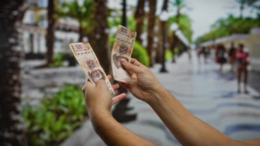 Bir şehir caddesinde Meksika pezosu tutan eller, canlı bir şehirde iş, yatırım ve finans özünü yakalıyor..