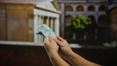 Brezilya Reais 'i elinde tutan adam şehir sokaklarında para basıyor, güneşli bir günde döviz ve iş dünyası sergiliyor..