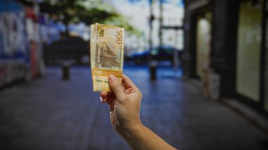 Kentsel bir sokak ortamında, para birimi ve açık hava iş faaliyetlerine odaklı finans ve yatırım kavramlarını temsil eden Norveç kronu banknotları.