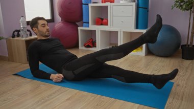 Spor salonunda spor salonunda spor yapan genç bir adam spor salonunda spor yapıyor ve spor ortamını geliştiren ekipmanlarla birlikte spor yapıyor.