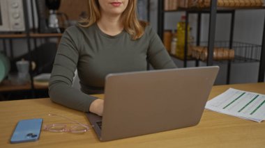 Ofisteki dizüstü bilgisayarda çalışan bir kadın yanında akıllı telefon ve gözlüklerle verimlilik ve odaklanma sergiliyor..