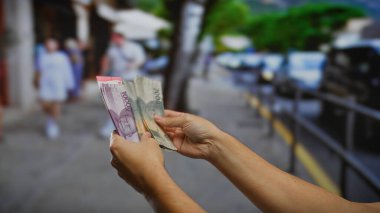 Endonezya rupiah 'ı elinde tutan eller şehir sokaklarında para topluyor, bir iş alışverişini ya da para alışverişini yakındaki bir adamla birlikte yakalıyor..