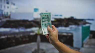 Kentsel sokak ortamında Çin Yuan banknotları, görünür mimarisi ve yolu olan bir şehir ortamında para birimi etkileşimi sergileniyor..