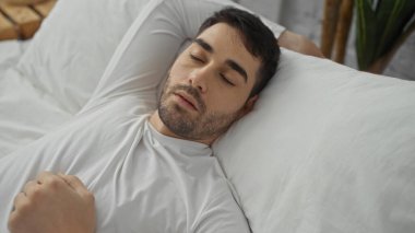 Yakışıklı bir adam, rahat bir yatak odasında huzurlu bir şekilde uyuyor. Evin içine yerleşiyor. Evin içinde rahatlık ve rahatlık hissi yayıyor..