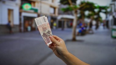 Kentsel caddede para birimine odaklanmış, iş bağlamında adamın kolunu açık havada tasvir eden, şehir hayatı ve finans konularını vurgulayan İzlanda Krona banknotu..