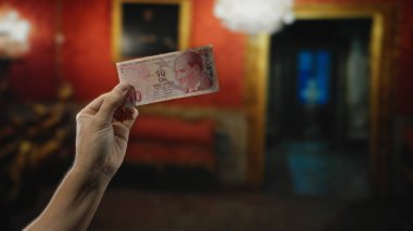 Müze odasında elinde Türk lirası banknot tutan bir adam, kapalı bir ortamda para ve kültür ortamını ön plana çıkarıyor..