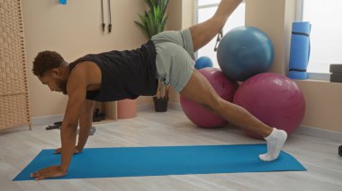 Spor salonunda spor salonunda yoga minderi üzerinde spor yapan genç bir adam..