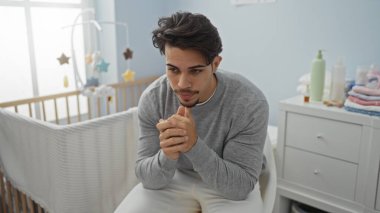 Genç adam düşünceli bir şekilde bir bebek odasında yanında bir beşiği ile oturmuş, derin düşüncelere dalmanın ve kapalı bir ortamda iç gözlem yapmanın özünü yakalıyordu.