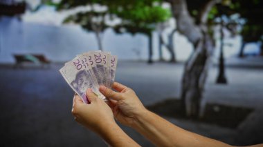 Şehrin göbeğindeki bir iş ya da yatırım temasını vurgulayarak, bir şehir ortamında iki eliyle İsveç kronunu tutan adam.