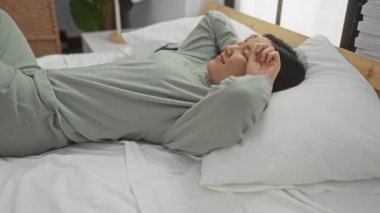 Bir kadın uyanıyor ve rahat bir yatak odasında rahat bir yatakta uzanıyor. Rahat bir sabah rutini sergiliyor. Huzur ve sükunetin çekici bir atmosferi var..