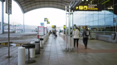 Açık hava havaalanı terminalinde yürüyen insanların bulanık görüntüsü çözünmüş tabela ile 1. terminalin işlek atmosferini yakalıyor..