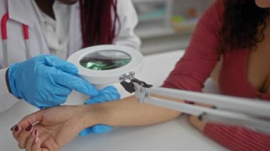 Doktor, bir klinikte büyüteçle hastanın kolunu muayene ediyor. Kadın doktor ve hasta ilişkilerinde sağlık ve tıbbi uzmanlık gösteriyor..