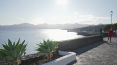 Bulanık arka plan, Lanzarote 'daki okyanus kıyısı manzarası, kanarya adaları, açık alanda yürüyen kadınların bulanık görüntüleri..