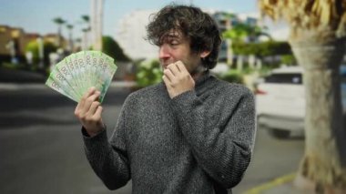 Hispanik bir adam, bir şehir caddesinde gergin bir şekilde Rus rublesi banknotları tutuyor, açık bir şehir zemininde çeşitli kültürel sembolleri harmanlıyor, küresel bir finansal senaryo ortaya koyuyor..